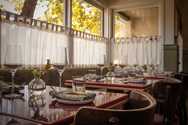 Tables set with wine glasses by the windows at Walson Wine Bar